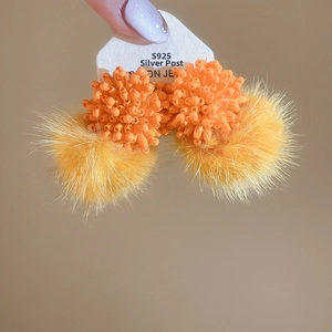 Detail of S925 silver needle earring featuring orange beaded ball and yellow fur pompom