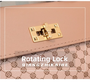 Detail of a pink-beige leather handbag showing the golden twist-lock closure with metal studs