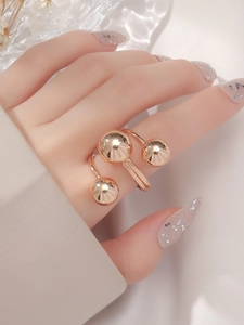 Detailed view of rose gold multi-sphere open ring on hand with shimmering background