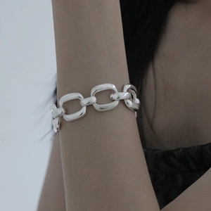 Close-up of a silver heavy-link chain bracelet on a model wrist with metallic luster