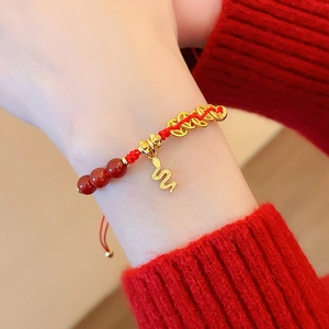Détail d'un bracelet en corde tressée rouge avec pendentif serpent doré et perles