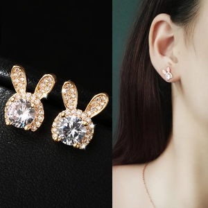 Détail macro et mannequin portant des boucles d'oreilles lapin en or et zircon