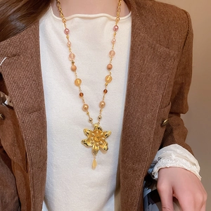 Détail du collier pendentif fleur avec perles sur femme en costume de velours