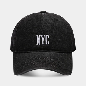 Close-up of NYC white embroidery detail on black washed denim baseball cap texture