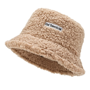 Detail of soft beige faux shearling bucket hat featuring a white embroidered fabric label