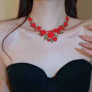 Macro detail of red rose necklace with green leaves and pearls on a model