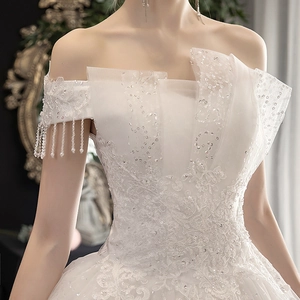Elegant off-the-shoulder white wedding dress with lace embroidery and pearl tassels