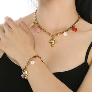 Close-up of gold chain necklace and bracelet set with enamel mushroom and carrot charms