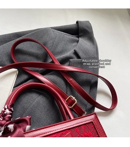 Detail of red bridal handbag featuring adjustable strap and elegant silk scarf decoration