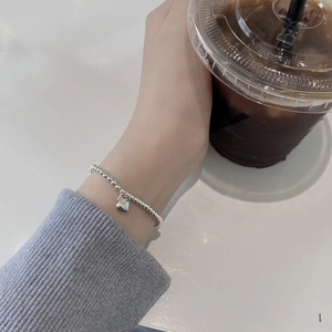 Lifestyle foto van een zilveren kralenarmband met hartjeshanger om de pols