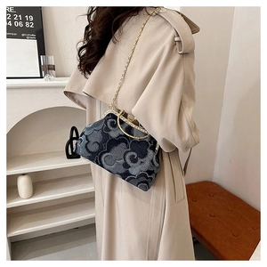 Detail of dark denim handbag featuring cloud patterns and golden chain strap for women