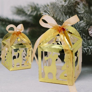 Golden laser-cut Christmas candy boxes featuring reindeer and tree patterns with silk ribbons