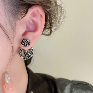 Macro shot of vintage silver hollow filigree double-sided stud earrings on model