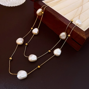 Macro view of double-layer baroque pearl necklace draped on a vintage wooden jewelry box