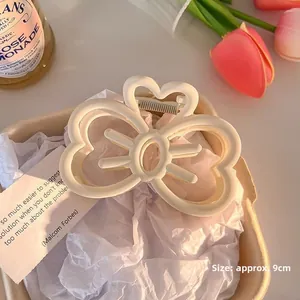Detailed view of a 9cm white matte bow hair claw clip with floral hollow design