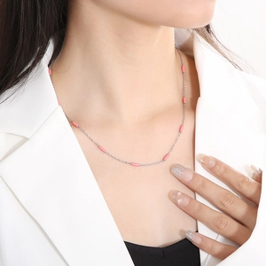Minimalist gold-plated titanium necklace with pink enamel accents worn by a model