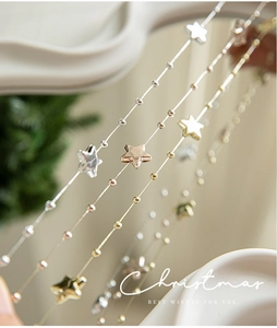 Macro shot of gold and silver star bead chains with festive Christmas tree decorations