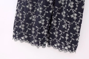 Close-up of white floral embroidery and scalloped hollow edges on a dark navy midi dress