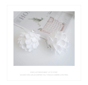 Detailed view of white petal-shaped Christmas foam ornaments with silver hangers