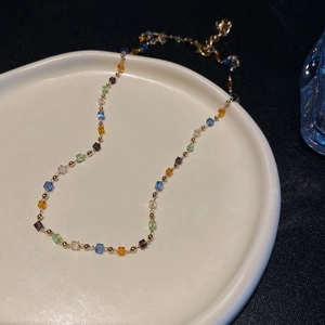 Macro detail of colorful crystal cube beads on a gold chain inside a ceramic dish