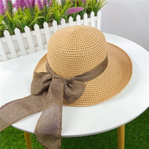 Detail view of woven straw sun hat featuring a dark coffee mesh bow for beach vacation