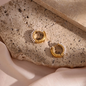 Close-up of 18K gold plated hoop earrings with white pearls on a silk fabric background