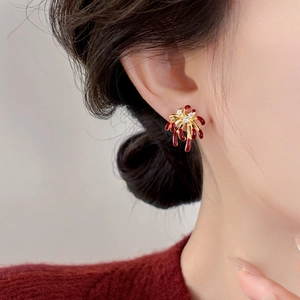 Macro detail of 18k gold plated firework earrings with red glaze and white zircon