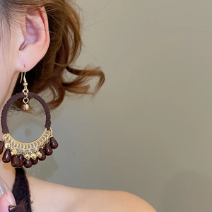 Close-up of bohemian hoop earrings with brown woven rope and dangling teardrop beads