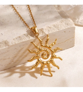 Close-up of golden sun pendant with spiral texture on a natural stone base