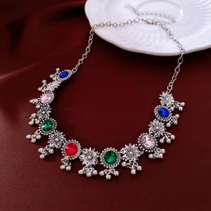 Close-up of vintage flower necklace with colorful gems and tiny bells on velvet