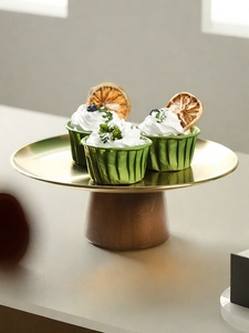 Detail of a golden metal dessert stand with dark wood base holding gourmet cupcakes