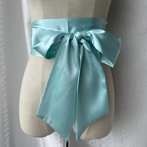 Vue détaillée de la ceinture en satin bleu tiffany nouée en arc sur la taille du mannequin