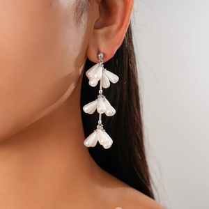 Macro view of long silver tassel earrings with tiered white teardrop pearls on model