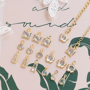 Macro shot of assorted gold-plated zircon pendants in multiple shapes on lace background