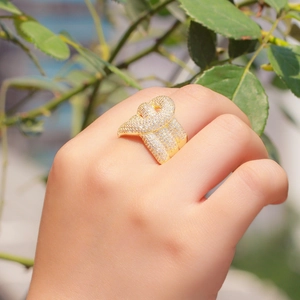 Luxurious gold knot ring with micro-paved AAA zircons on a hand with greenery background