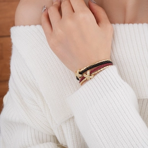 Detail of gold plated double-layer woven bracelet with zircon cross charm on model