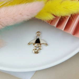 Macro detail of gold-plated umbrella charm with black and white enamel and rhinestones