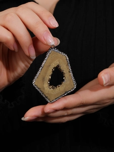 Macro detail of natural geode pendant with golden crystals and rhinestone edge inlay