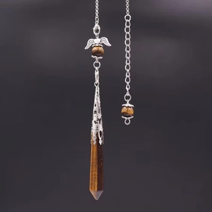 Macro shot of tiger eye stone crystal pendulum with silver heart wing metal detail
