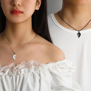 Detail of couple interlocking heart pendants in silver and black on models neck