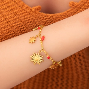 Bohemian gold chain bracelet featuring sun and star pendants with red beads on a knit sleeve