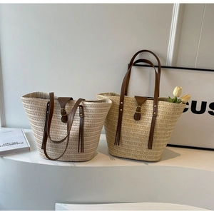 Detailed view of beige straw tote bags with brown leather handles and tulip flowers