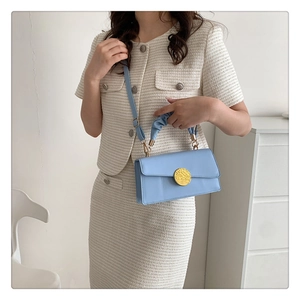 Détail du sac bandoulière bleu clair avec boucle dorée et poignée plissée