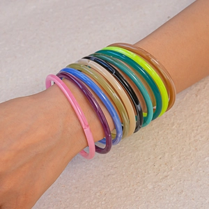 Stackable colorful acrylic resin bangles with a smooth glossy finish on a wrist
