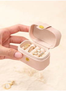 Close-up of pink portable jewelry box with ring slots and golden buckle in hand