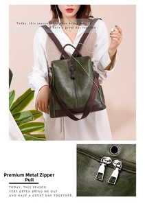 Detail of silver metal zipper puller and dark green PU leather texture on backpack
