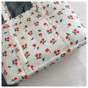 Close-up of white tote bag featuring cherry prints and detailed exterior pocket design