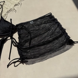 Vue détaillée de la texture du tissu en maille pailletée noire sur jupe de plage