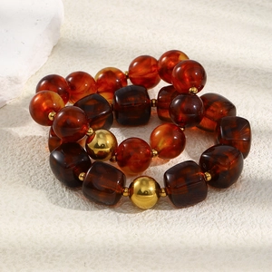 Macro view of amber resin beads and gold spheres on a minimalist beaded bracelet