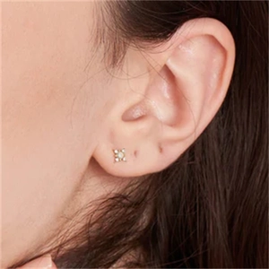 Close-up of elegant gold starburst stud earring featuring inlaid crystals on a model's ear